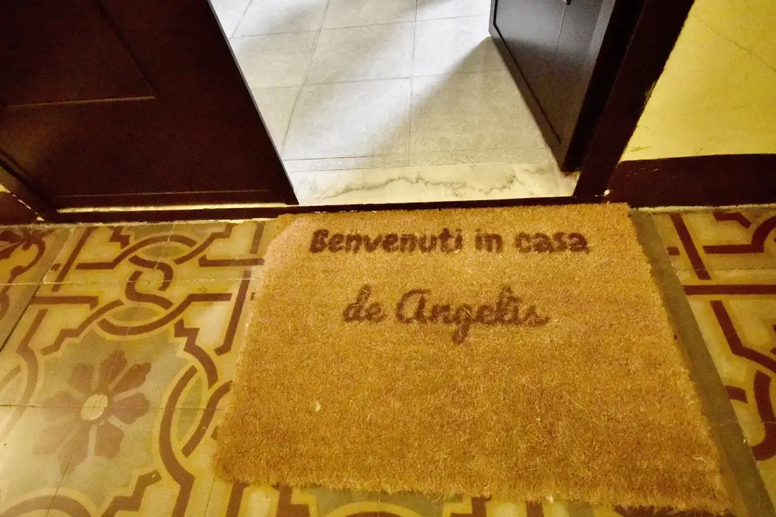 An entrance with an open doorway and a welcome mat on patterned tile flooring.