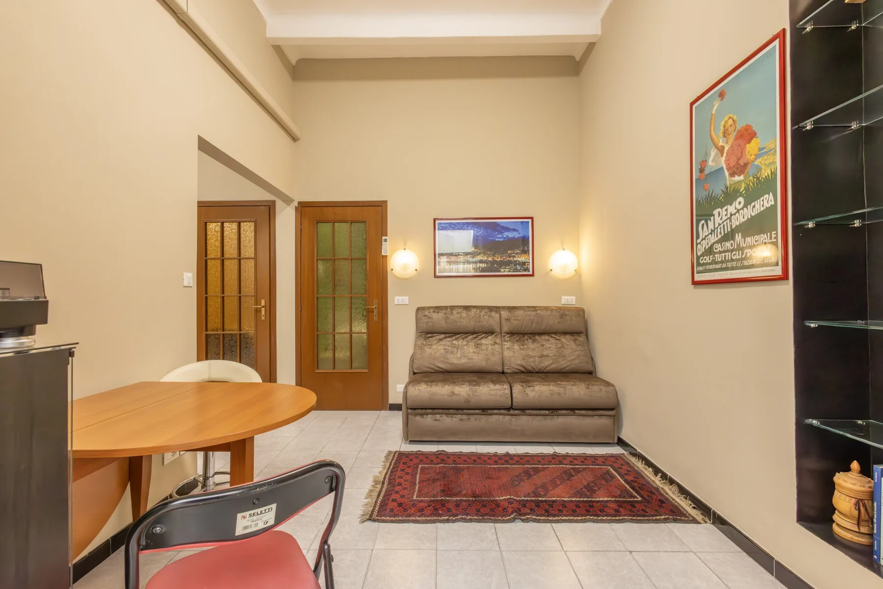 A living room with a sofa, rug, and a wooden dining table.