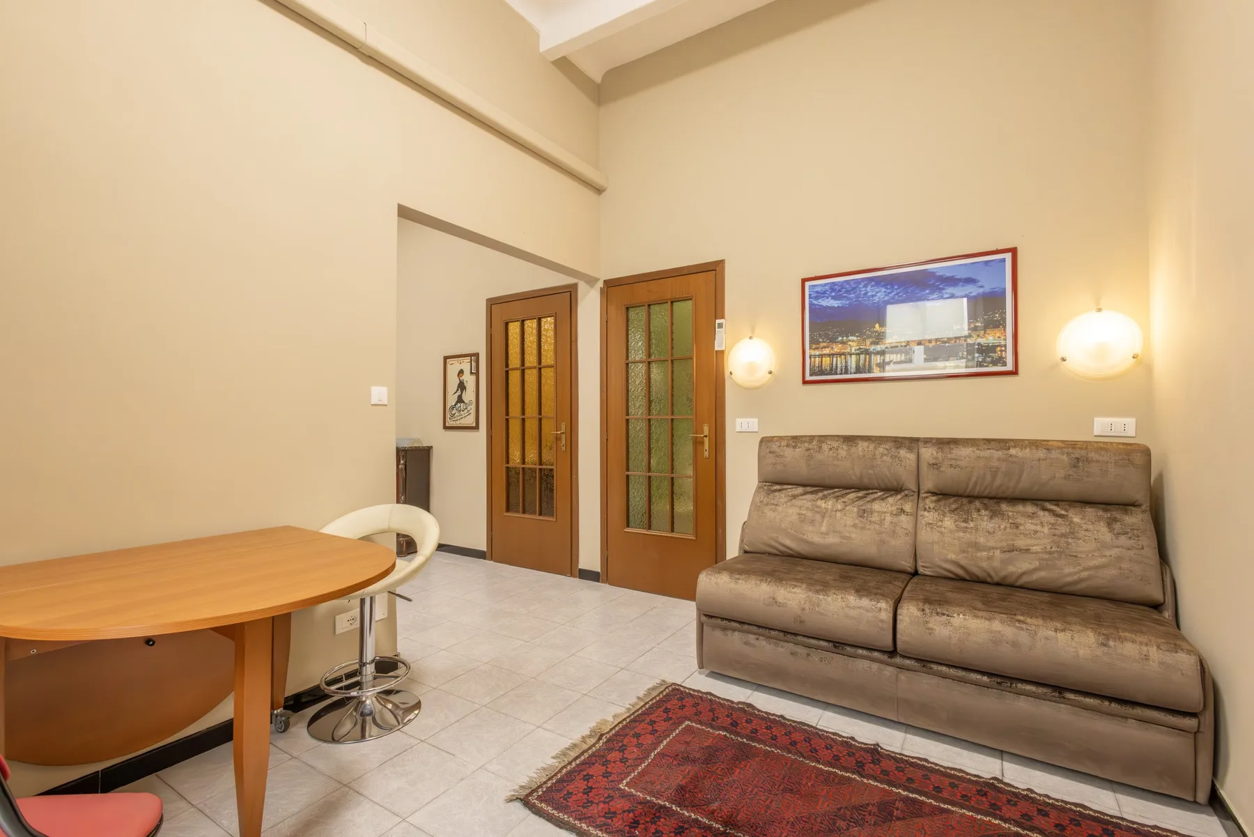 A living area with a sofa, a small table, and a patterned rug.