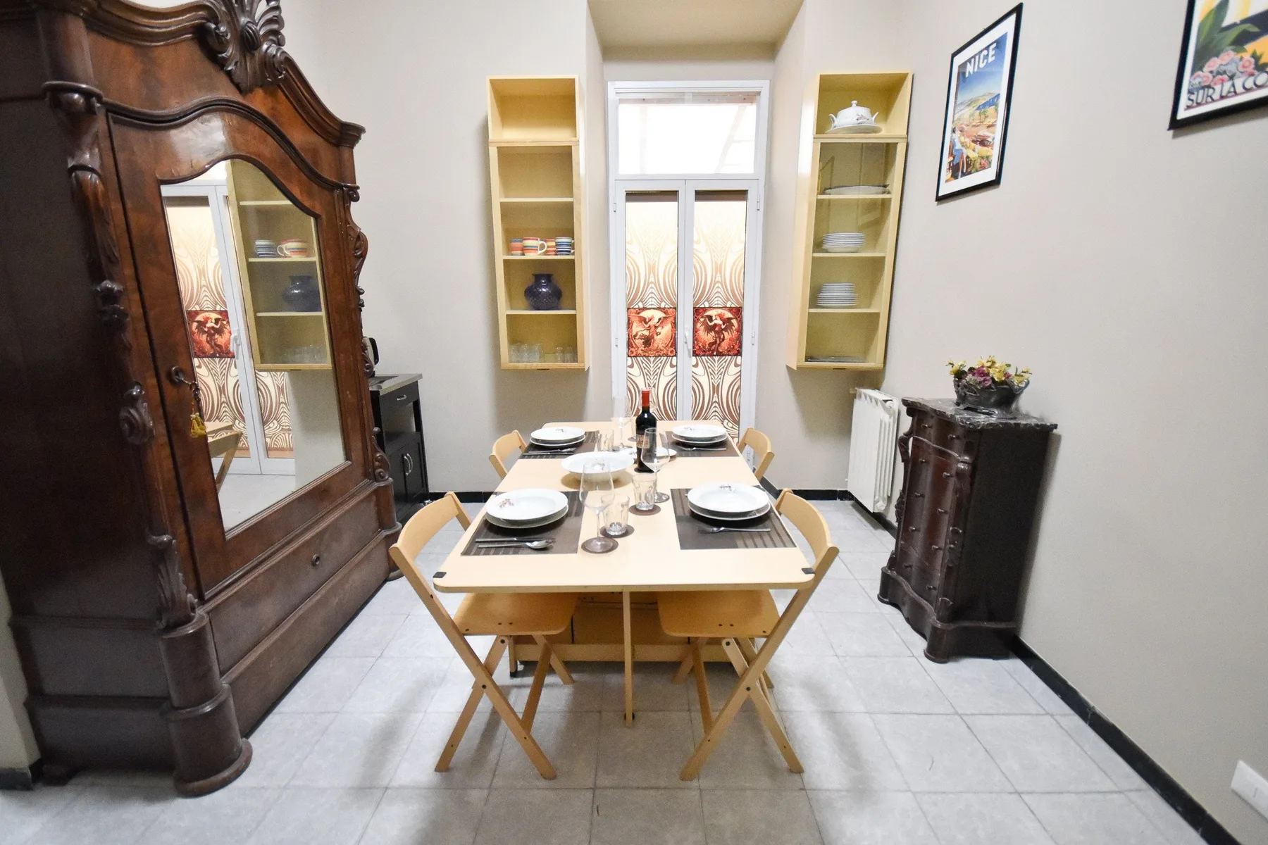 A dining area with a table and chairs beneath two wall shelves.