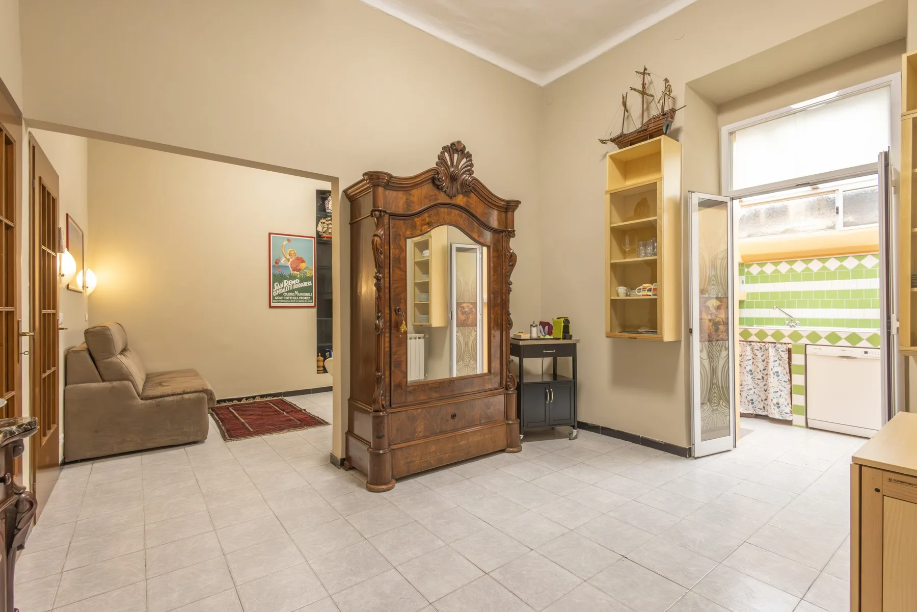 A tiled interior room features an ornate wooden wardrobe and a seating area.
