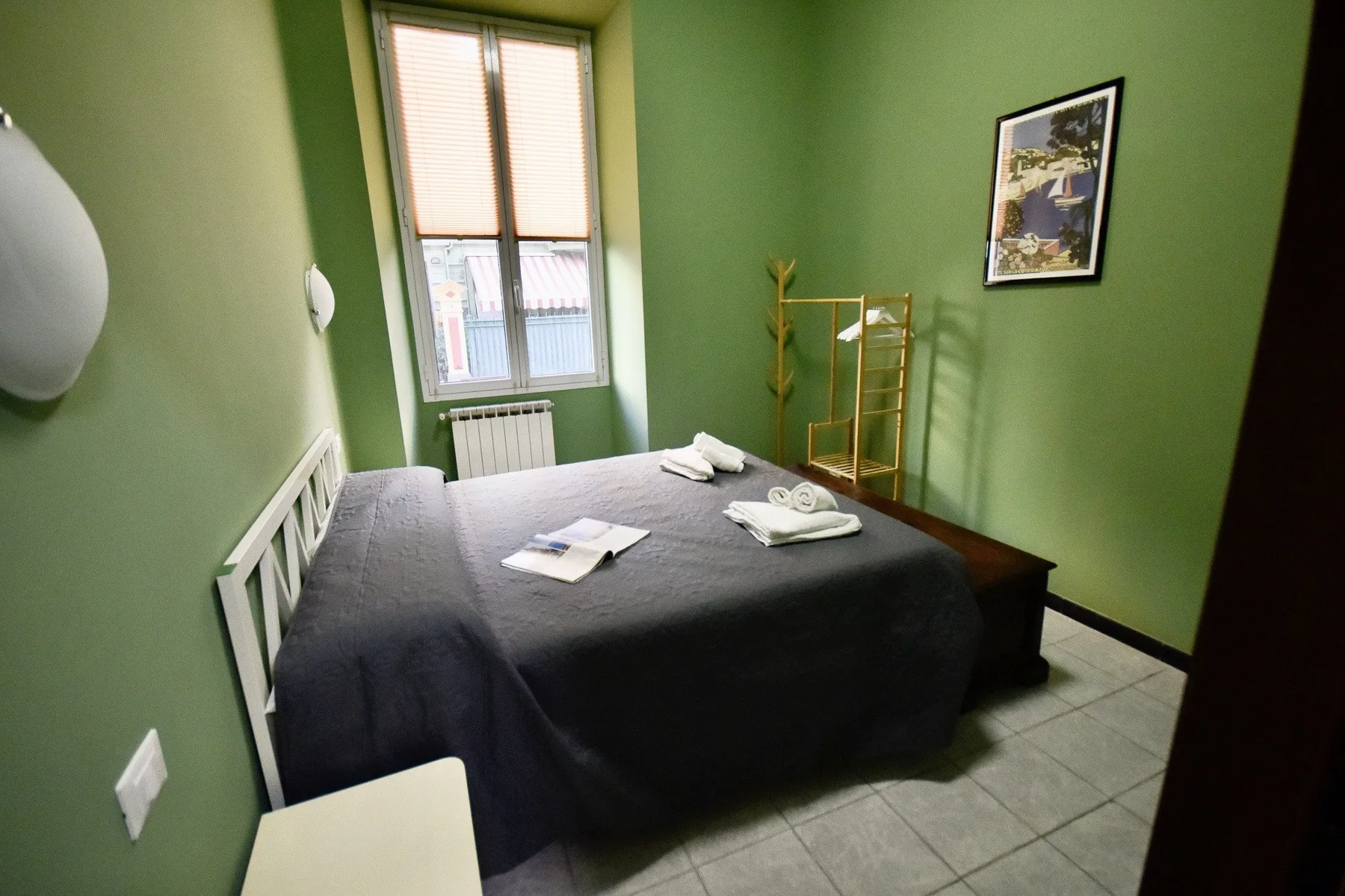 A bedroom with a bed, green walls, and a window.