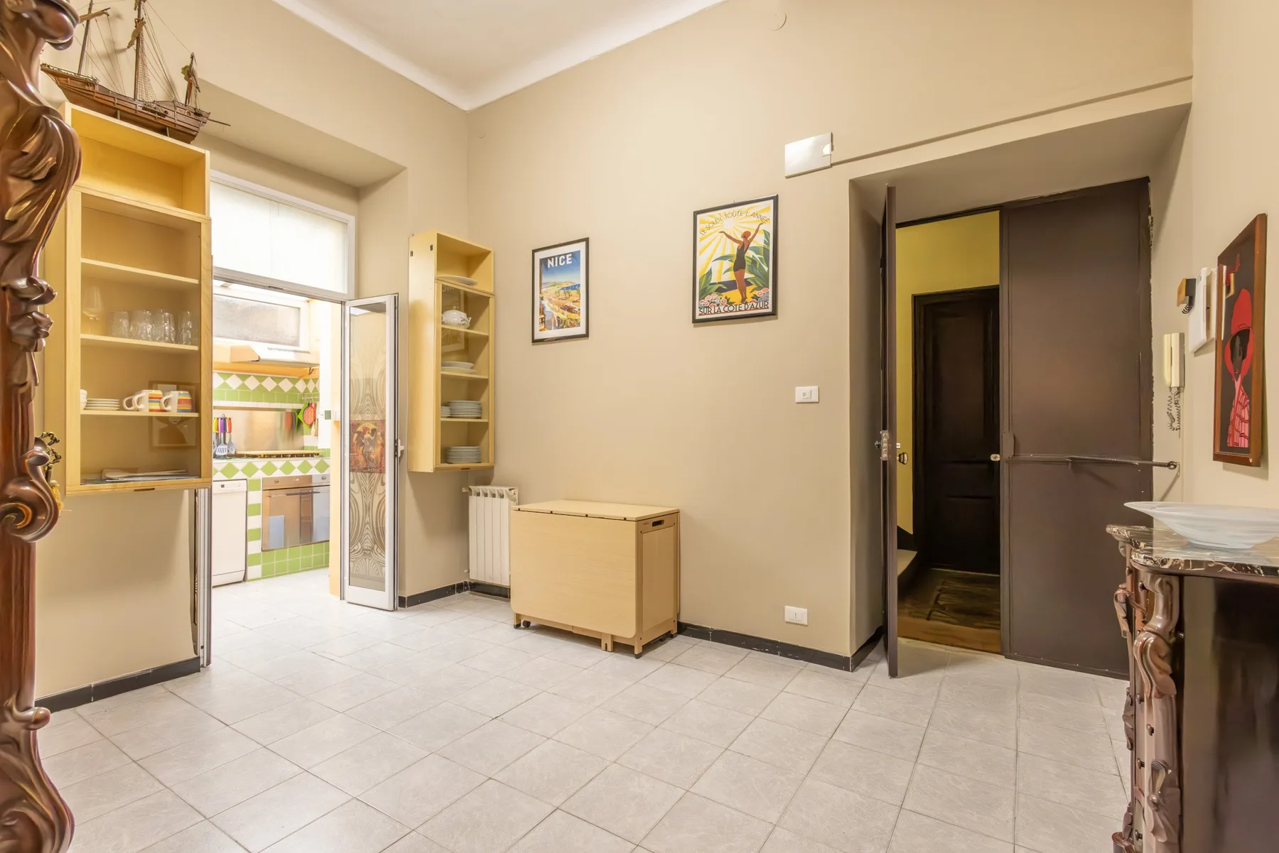 A tiled room with open shelving, a small cabinet, and a doorway.