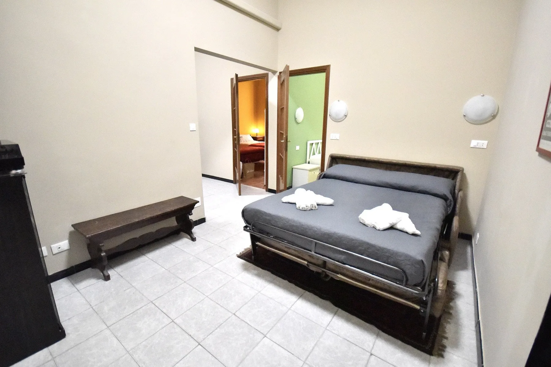 A bedroom with a double bed and an open doorway leading to another room.