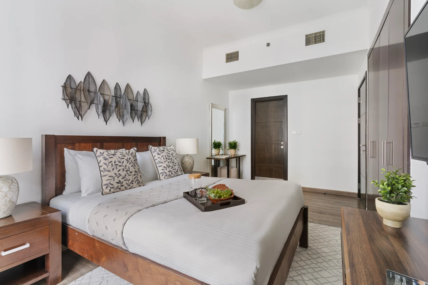 Un dormitorio luminoso con una cama tendida y arte decorativo en la pared.
