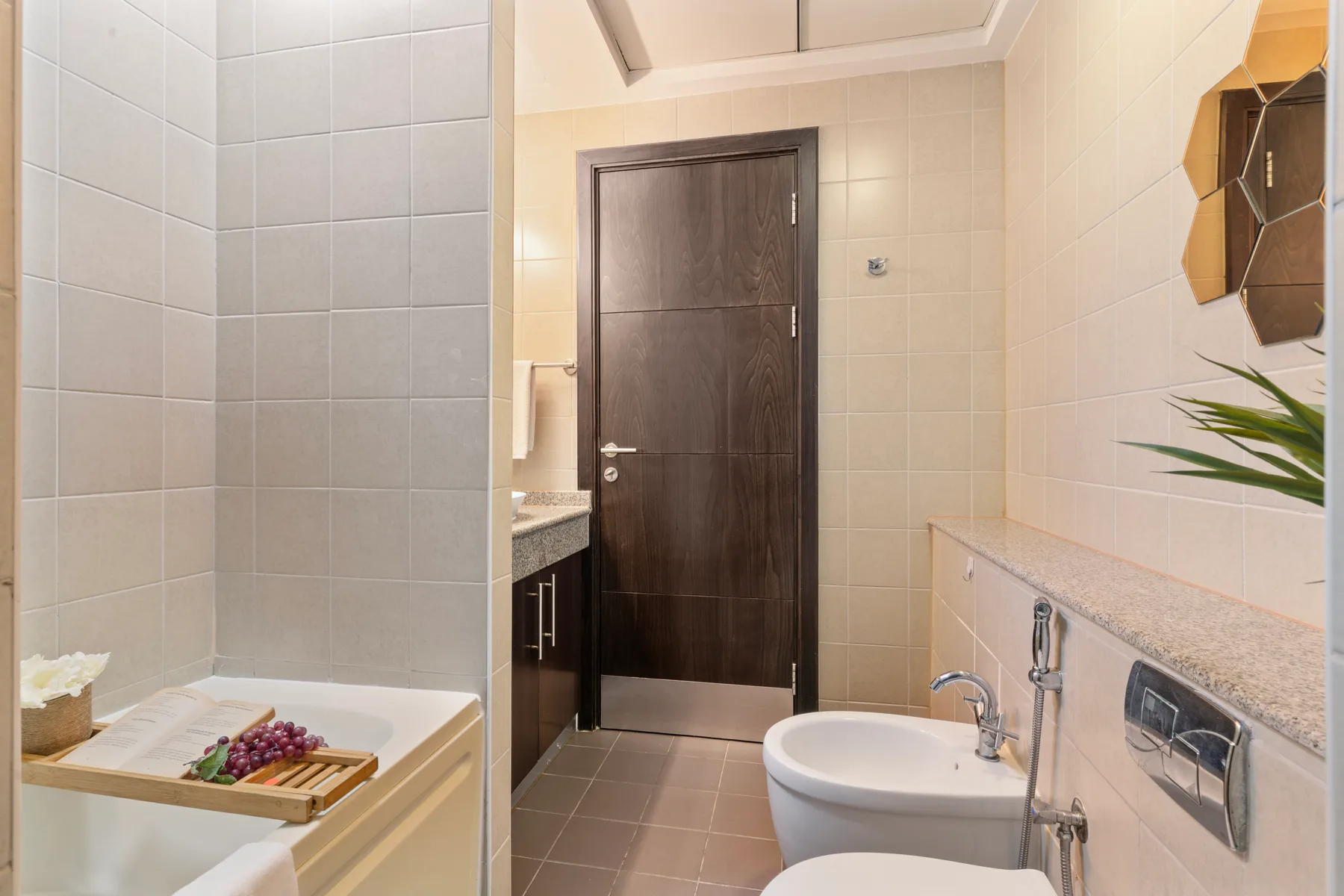 Un baño con azulejos, una puerta oscura y una bañera.