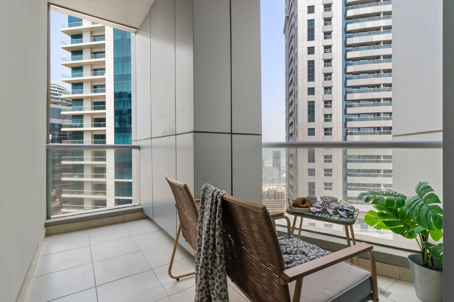 Una luminosa zona de estar en el balcón ofrece vistas de edificios altos cercanos.