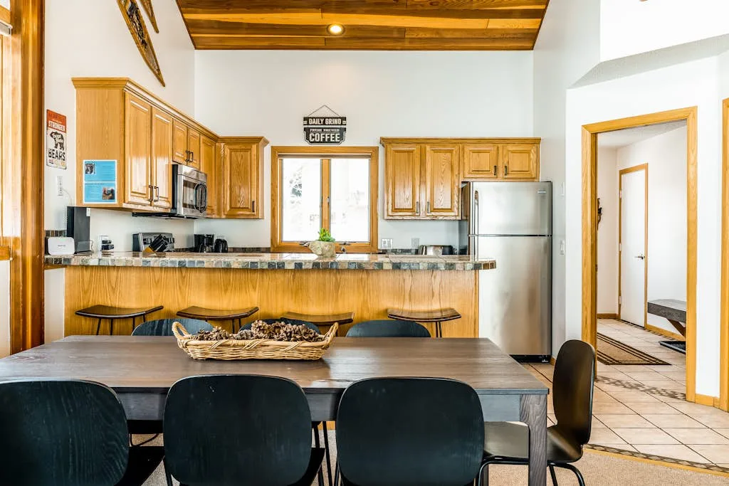 A kitchen and dining area with a wooden counter, table, and dark seating.