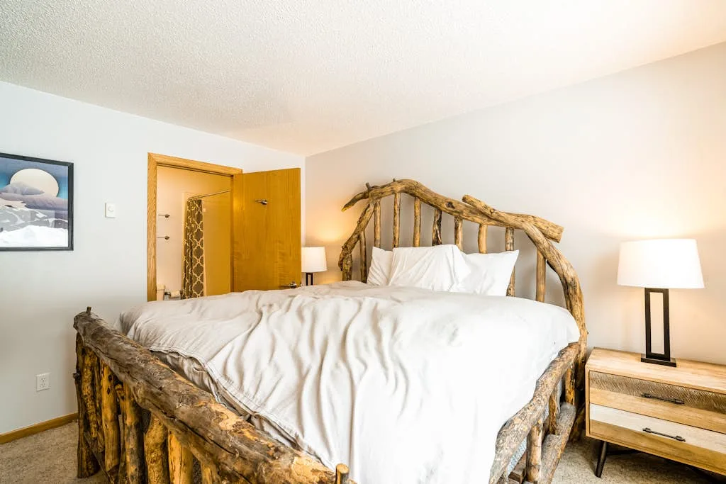 Bedroom with a bed framed by rustic wooden branches and bedside tables.