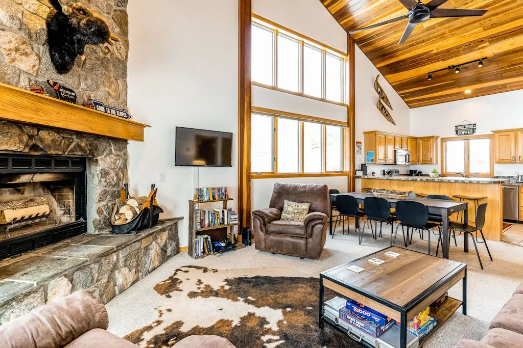 A spacious living area with a stone fireplace, seating, and an open kitchen.