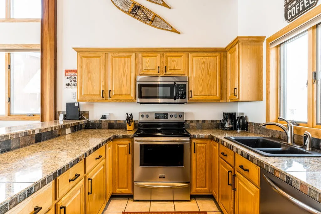 Una cocina con gabinetes de madera, encimeras oscuras y una estufa de acero inoxidable.