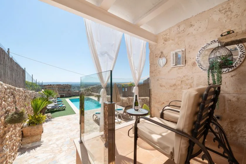 A patio with seating overlooks a swimming pool and the sea.
