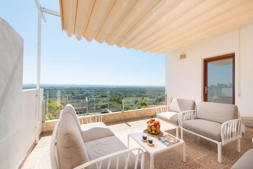 A covered outdoor seating area overlooks a green landscape.
