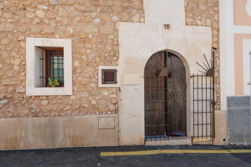A stone building facade with an arched doorway and barred windows.