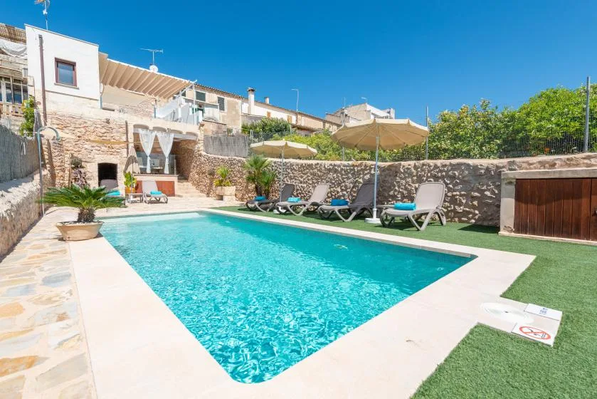 An outdoor swimming pool bordered by lounge seating and stone walls.