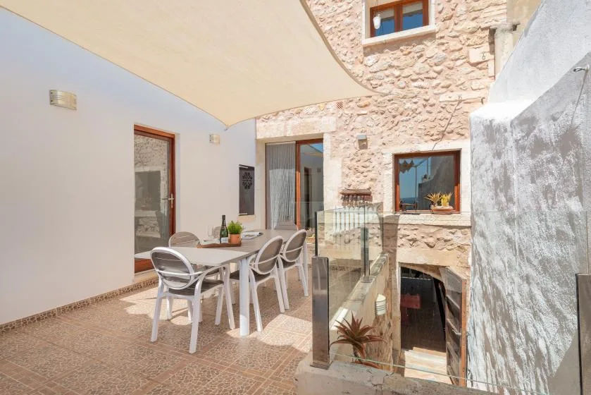 A sunlit stone courtyard with outdoor seating beneath a large shade canopy.