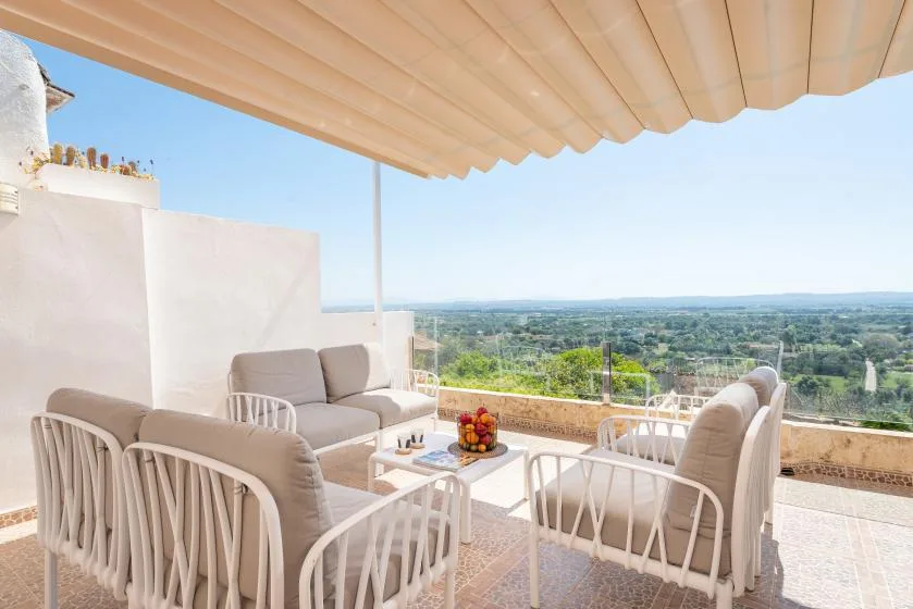 An outdoor seating area under a canopy overlooks a green landscape.