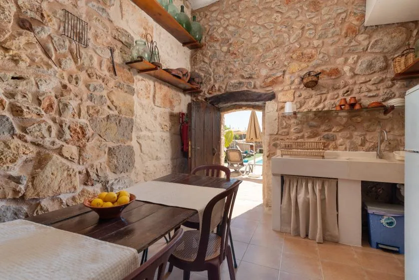 A stone-walled dining area with a table beside an open doorway.
