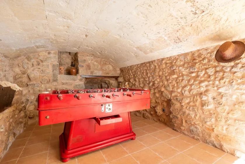 A stone-walled game room with a red foosball table.