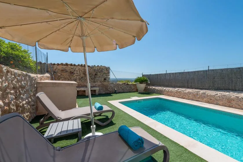 An outdoor swimming pool beside lounge seating on a sunny terrace.
