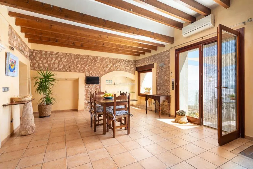 A dining area with a wooden table and chairs beneath exposed ceiling beams.