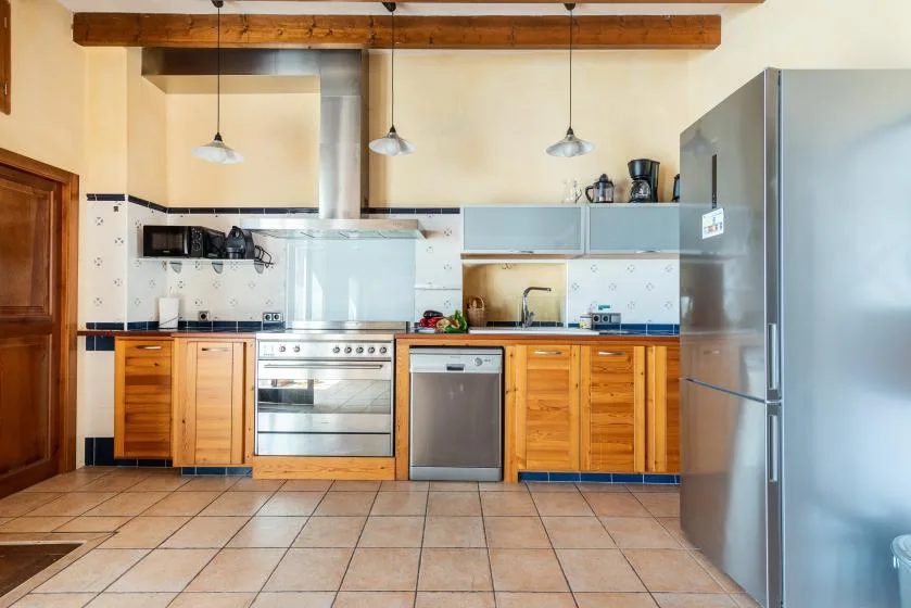 A kitchen with wooden cabinets, a stove, and a large refrigerator.