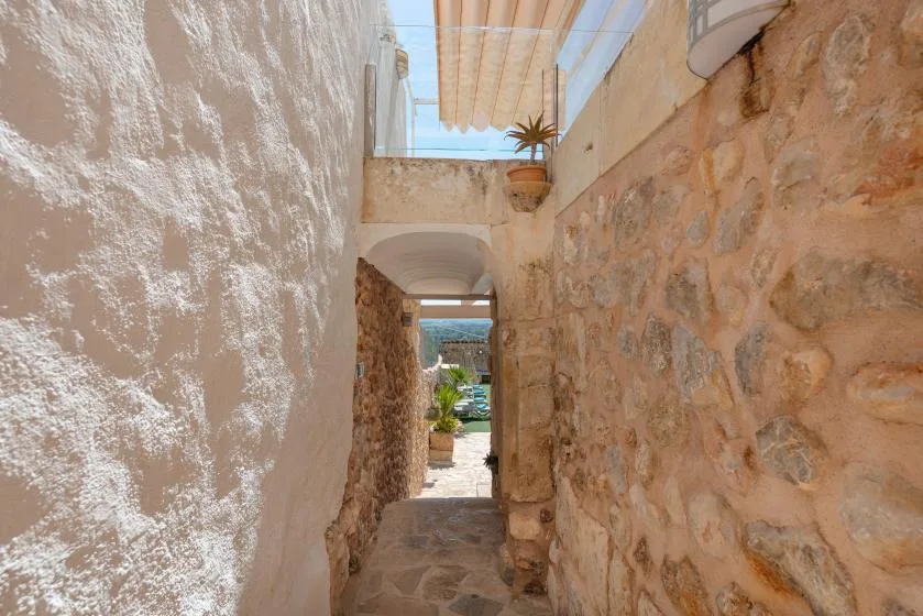 A narrow stone passage opens onto a sunlit outdoor area.