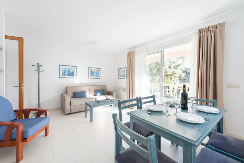 A bright living and dining room with a table set beside the window.