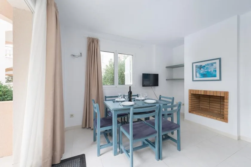 A dining area with a table and seating beside a window and fireplace.