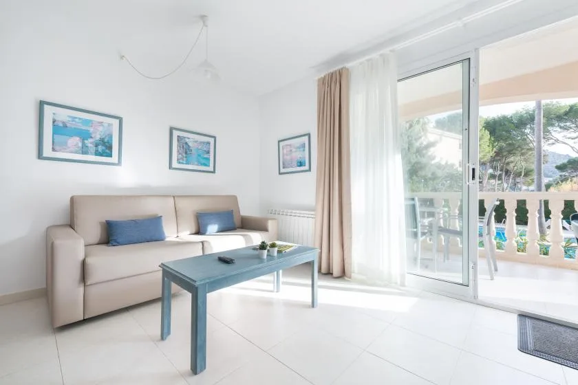 A bright living room has a sofa, coffee table, and glass doors opening onto a balcony.