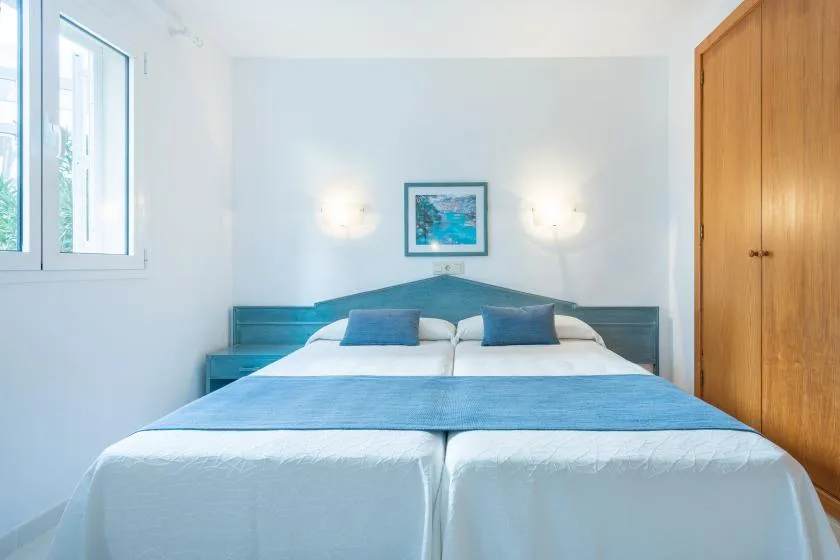 A bedroom with a double bed, blue bedding, and a framed picture above the headboard.