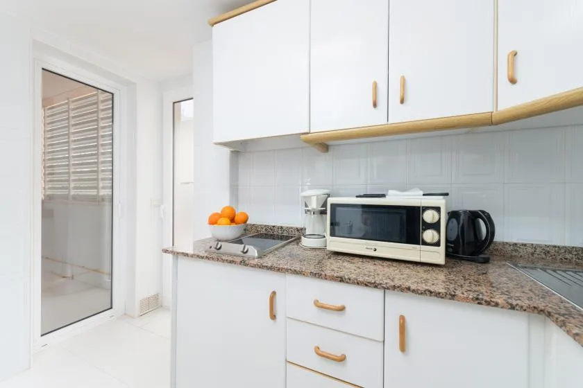 A bright kitchen with white cabinets, a countertop, and small appliances.