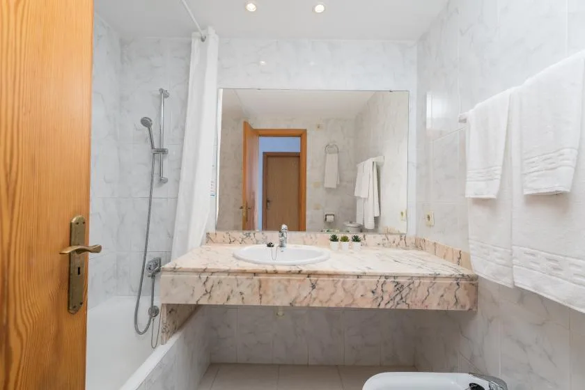 A bright bathroom with a wide sink counter and wall-mounted towels.