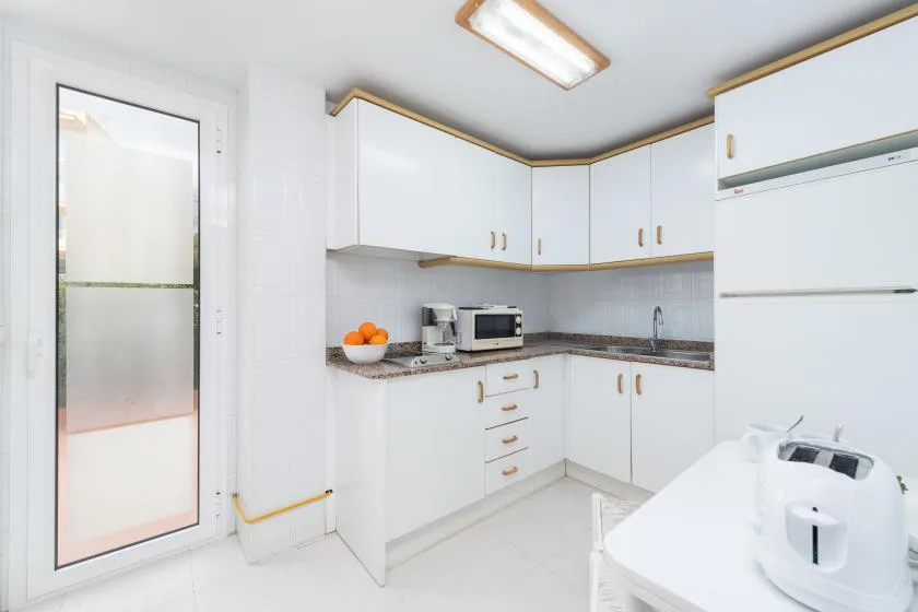 A bright kitchen with white cabinets, a countertop, and small appliances.