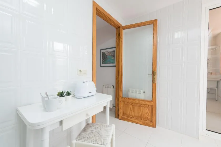 A bright tiled bathroom with a white vanity and a wooden-framed door.