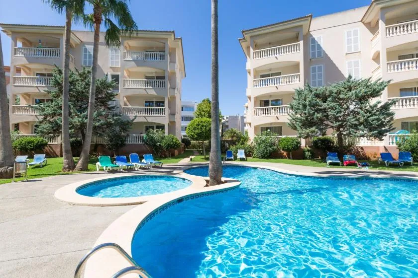 An outdoor swimming pool sits among apartment buildings and landscaped grounds.