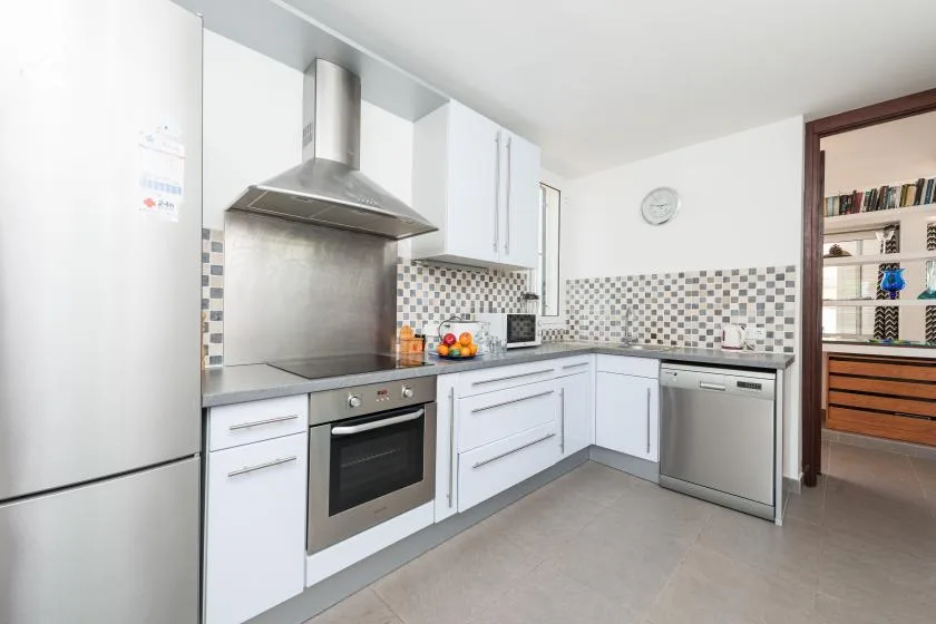 Una cocina luminosa con gabinetes blancos, una estufa y un salpicadero de azulejos.