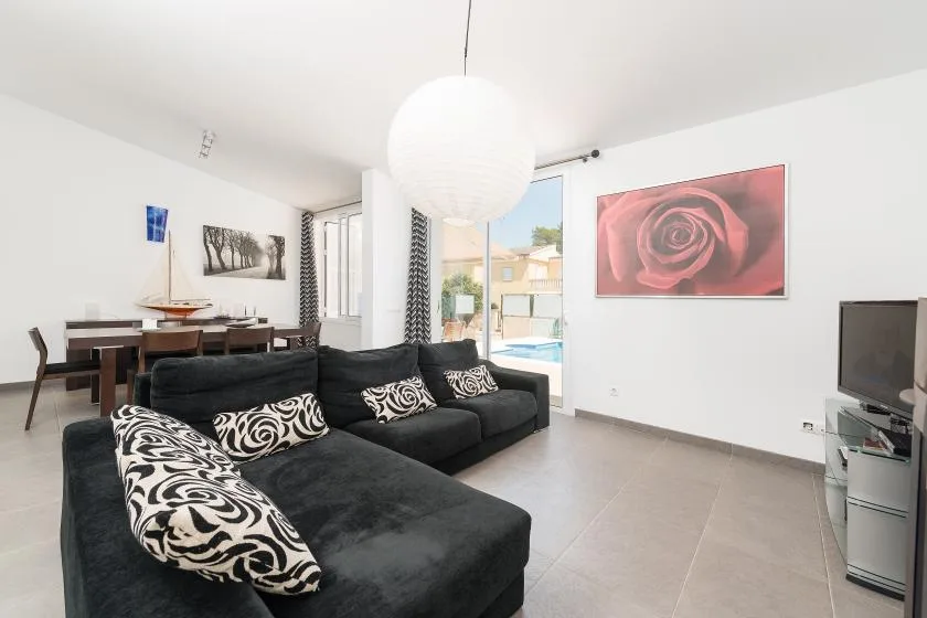 Una sala de estar con asientos oscuros, una mesa de comedor y un cuadro grande de una rosa.