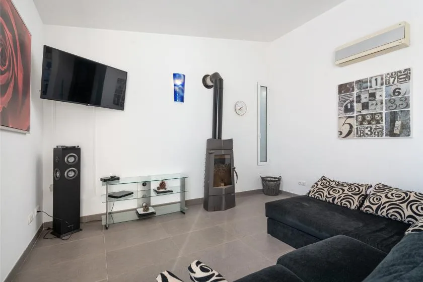 Una sala de estar con un sofá seccional oscuro, televisor y estufa independiente.