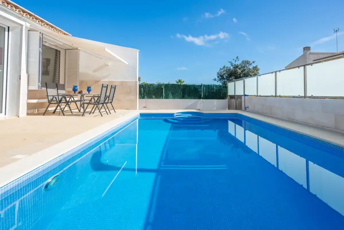 Una piscina junto a un patio con asientos al aire libre.