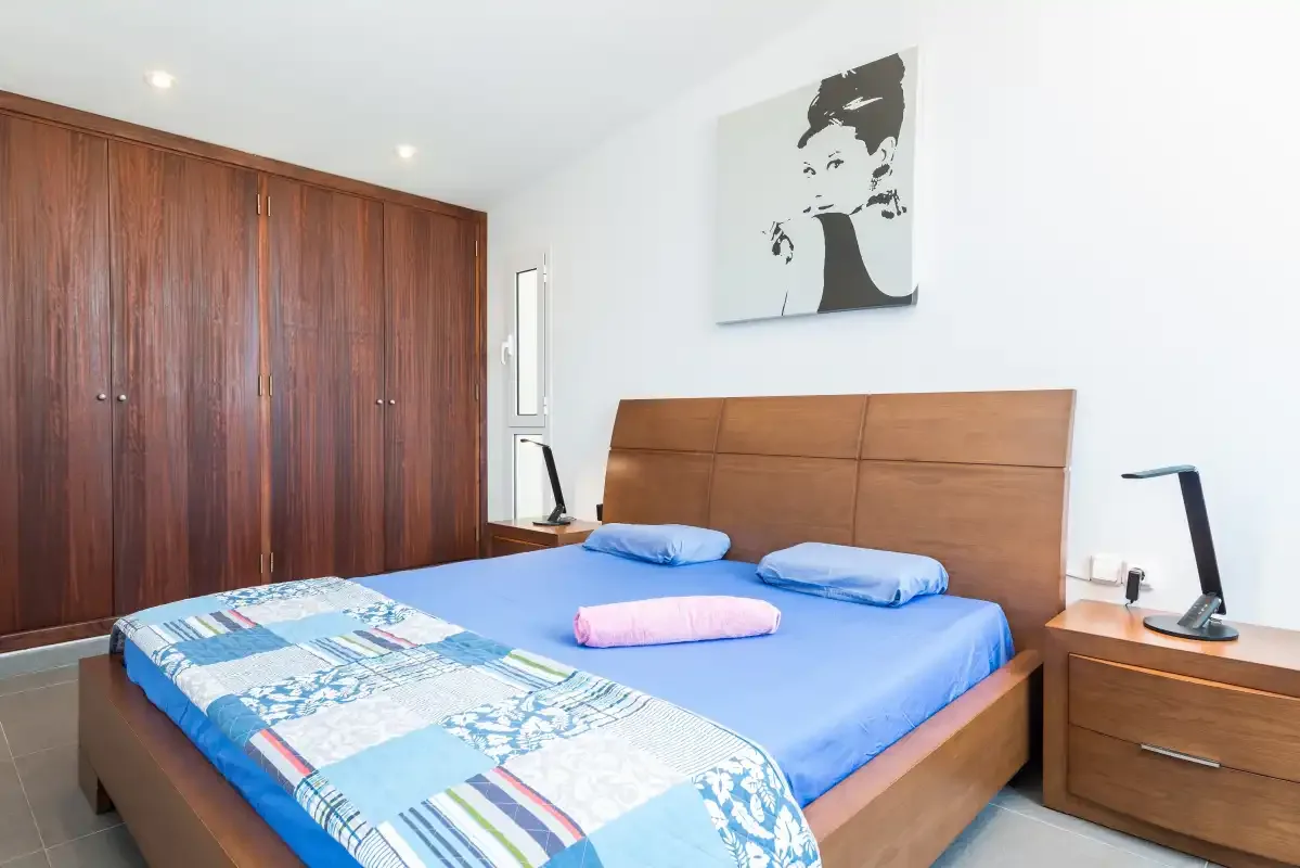 Un dormitorio con una colcha azul y armarios empotrados de madera.