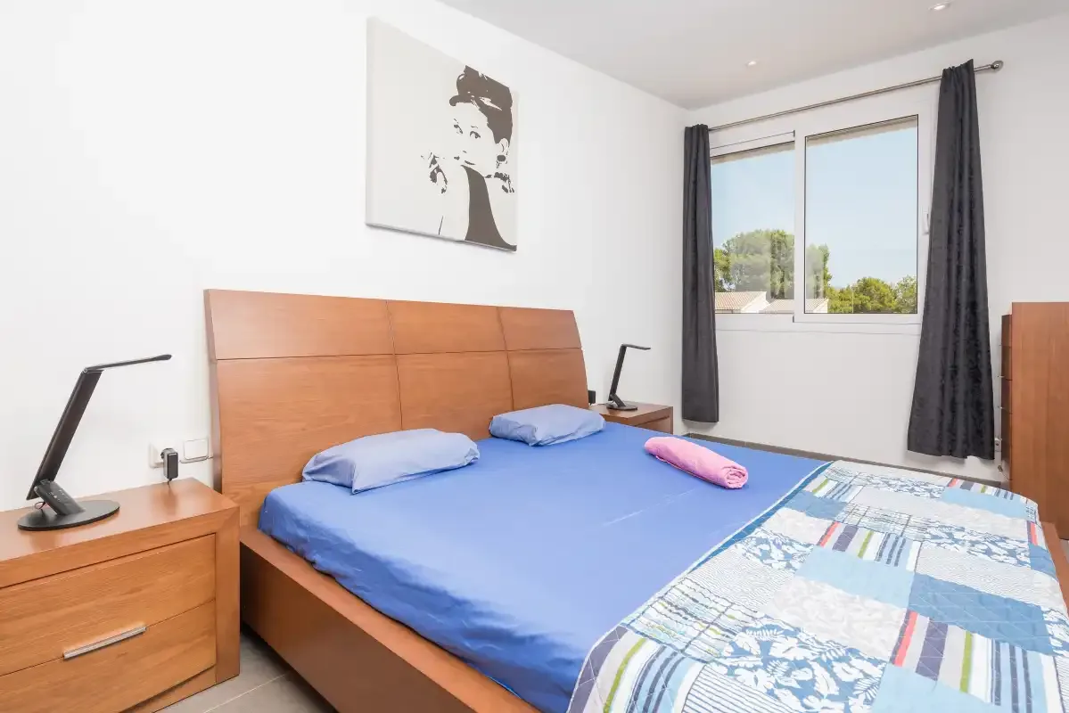Un dormitorio con una cama azul, un cabecero de madera y una ventana.