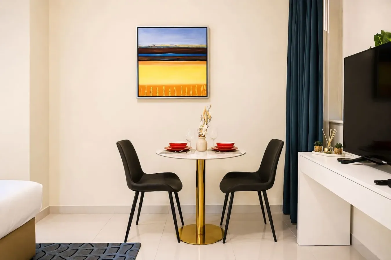 Comedor con una mesa pequeña, dos sillas y un cuadro colorido.