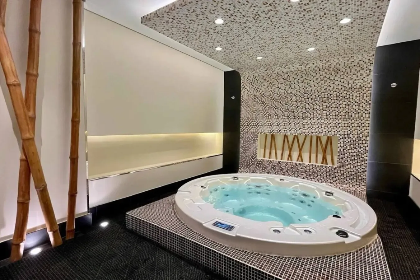 A tiled indoor spa room with a large bubbling hot tub.