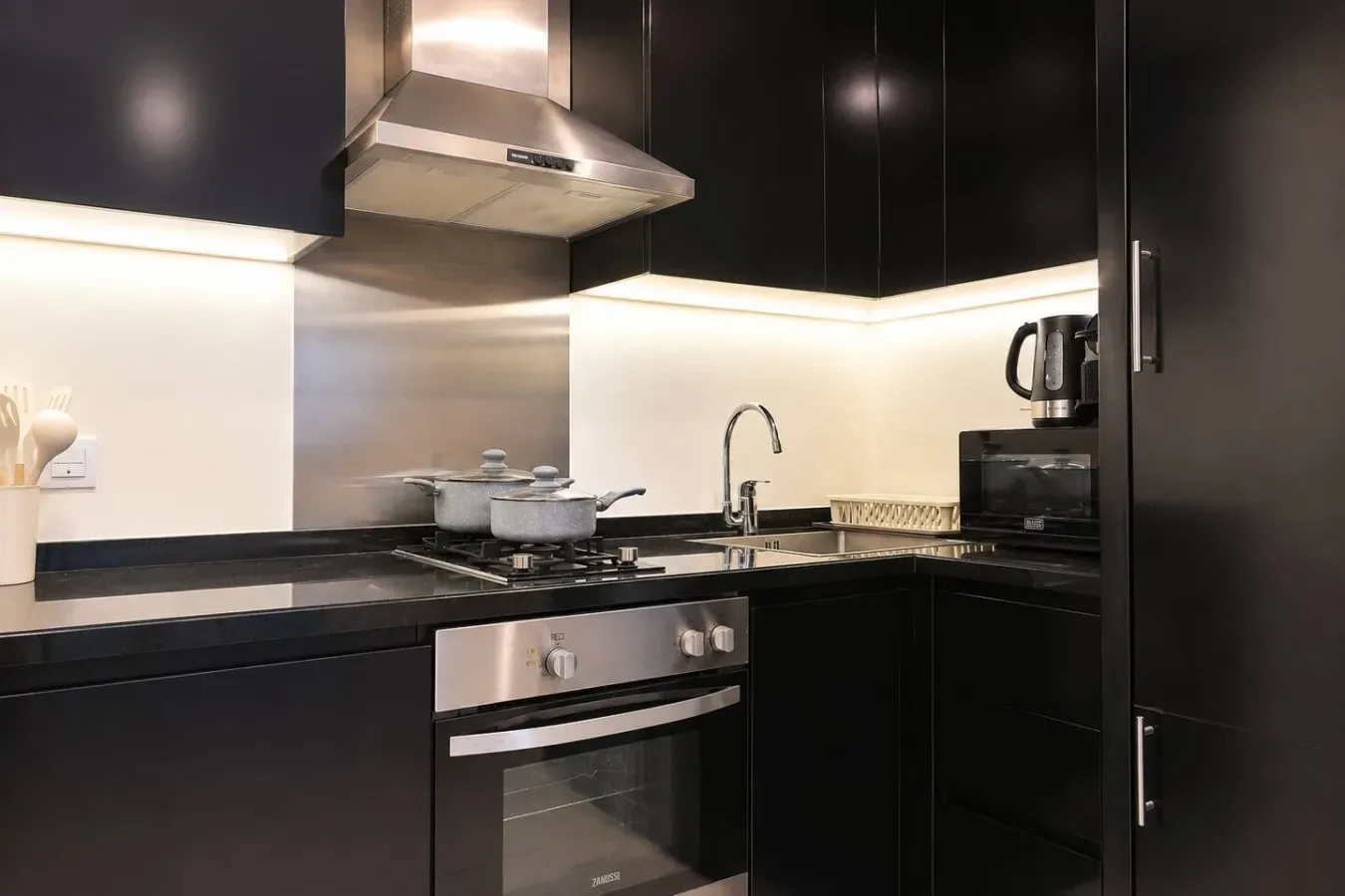Una cocina moderna con gabinetes oscuros, una estufa y un fregadero.