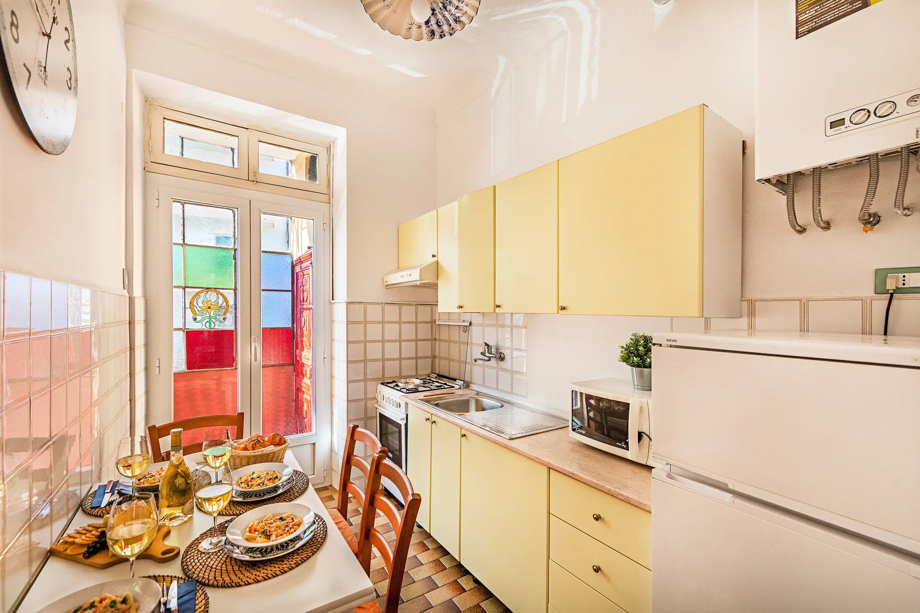 A bright kitchen with yellow cabinets and a dining table set for a meal.