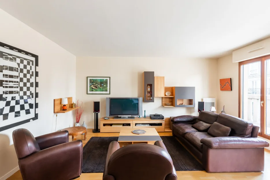 A living room with dark seating, a television, and a coffee table.
