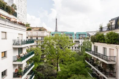 A leafy courtyard between apartment buildings, with the Eiffel Tower visible in the distance.