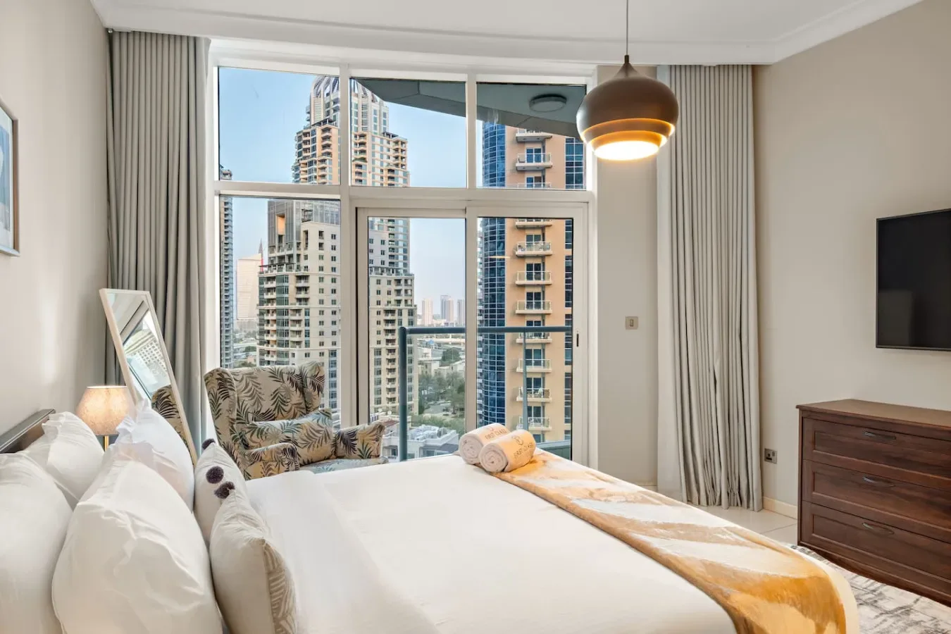 Un dormitorio luminoso con una gran ventana y vistas a edificios altos cercanos.