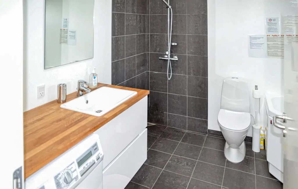 Un baño con una encimera de madera, lavabo, ducha e inodoro.